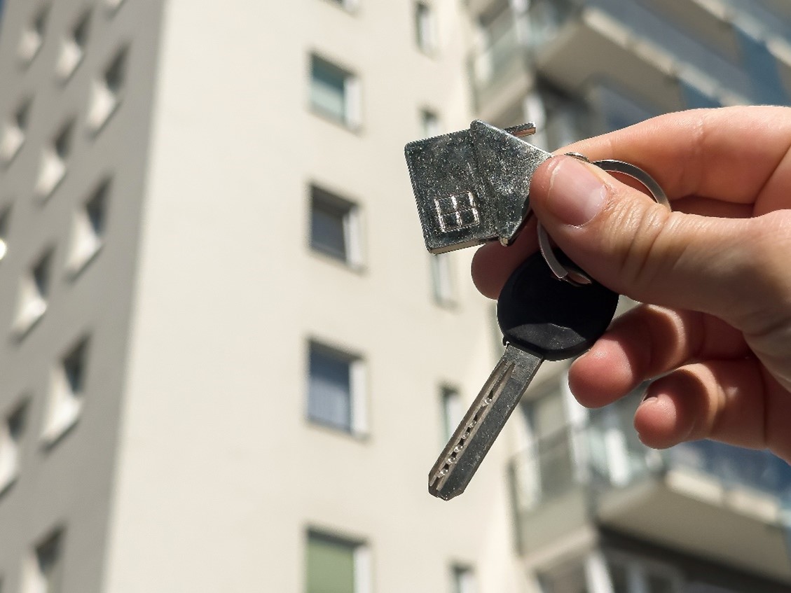 Hand holding keys by building.