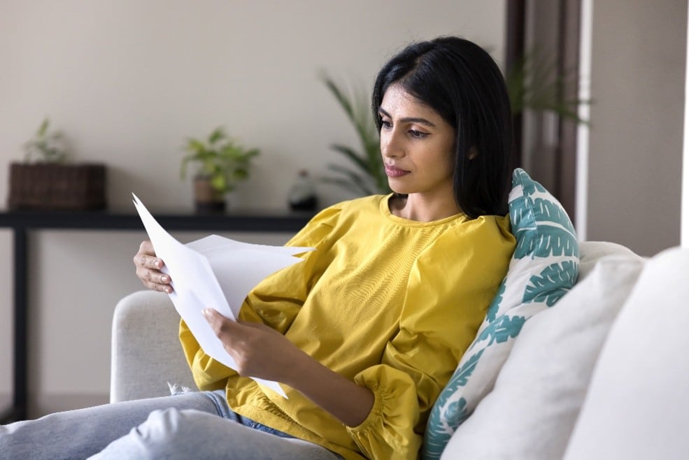Woman reading papers on sofa.